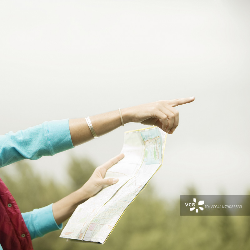 女士手持指向前方的地图的特写镜头图片素材