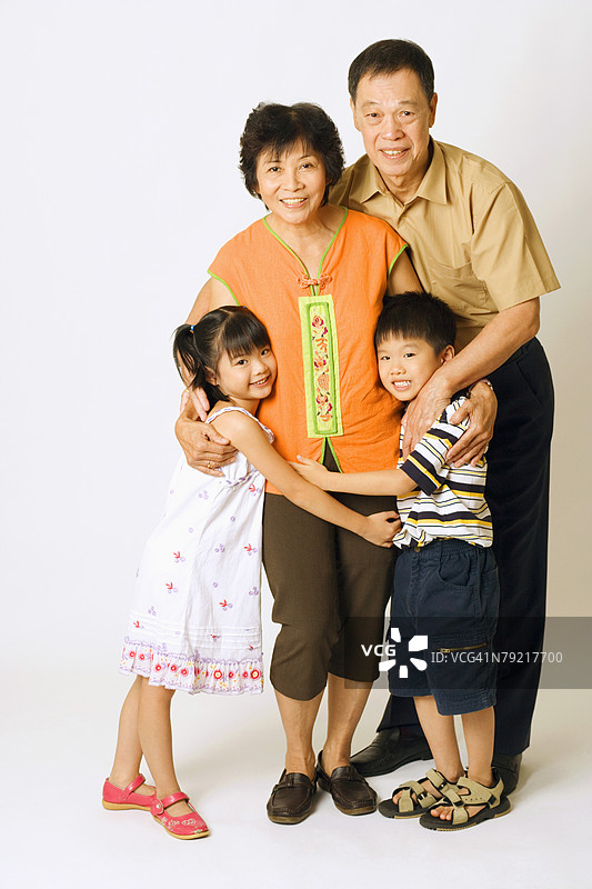 一位老年男性和一位女性与他们的孙子孙女们站在一起的肖像图片素材