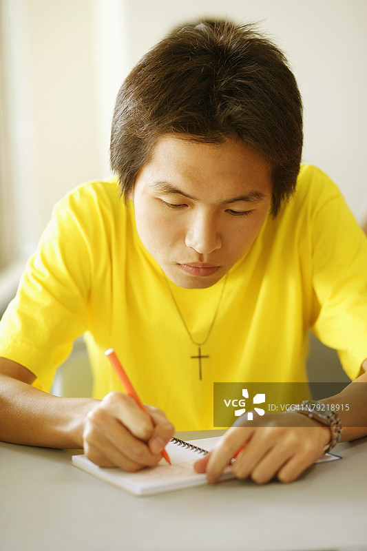 年轻男子在笔记本上写字的特写镜头图片素材