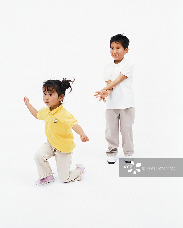 一个小男孩微笑着，他的妹妹跪下来。图片素材