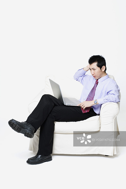 坐在扶手椅上使用笔记本电脑的商人图片素材