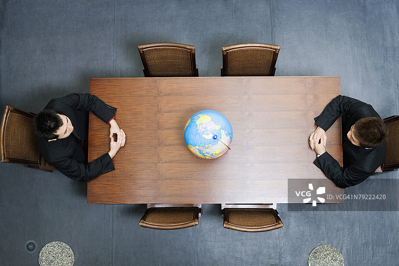 高角度视图的两位商人在会议桌前坐着图片素材