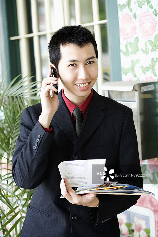 一位商人手持文件，正在用手机通话的肖像图片素材
