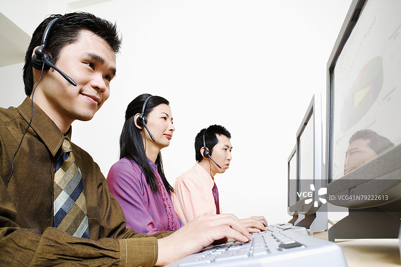 三名客服代表在电脑上工作图片素材