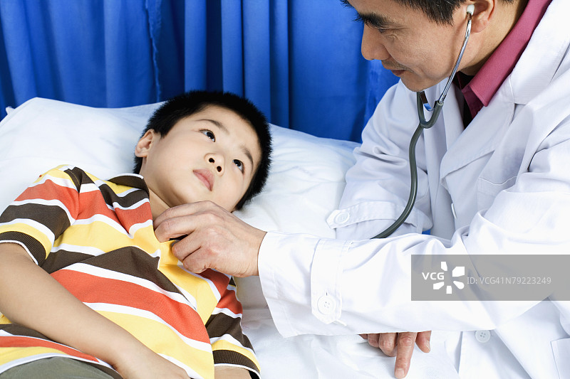 男医生用听诊器检查男孩侧面图片素材