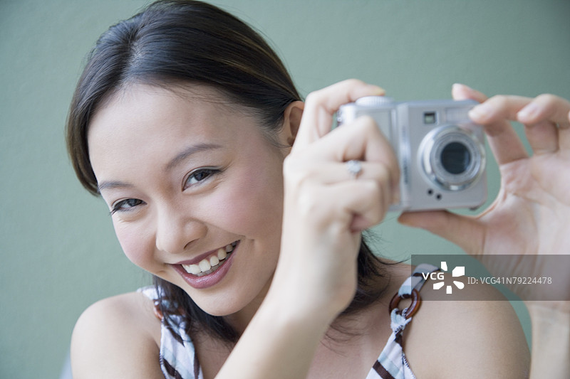 年轻女性用数码相机拍照的肖像图片素材