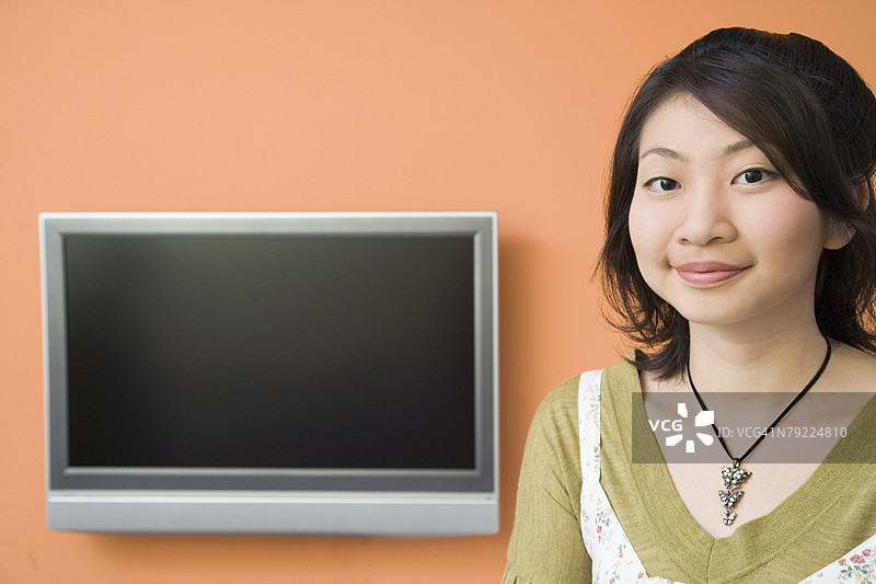 年轻女性微笑着，背景是电视屏幕图片素材