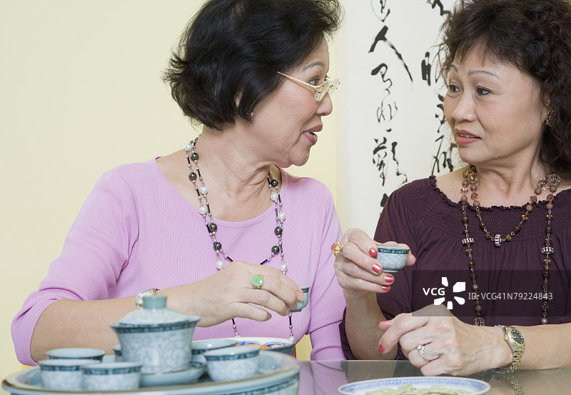 坐在桌旁端着茶杯的两位年长妇女图片素材
