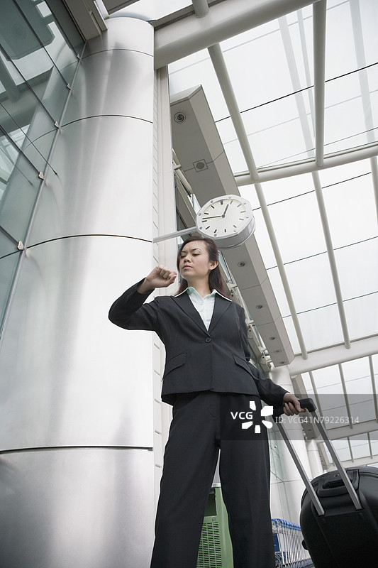 低角度视图的女商人在机场休息室查看手表图片素材