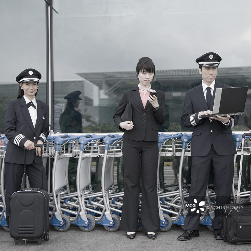 女乘务员与两名飞行员在机场站立图片素材