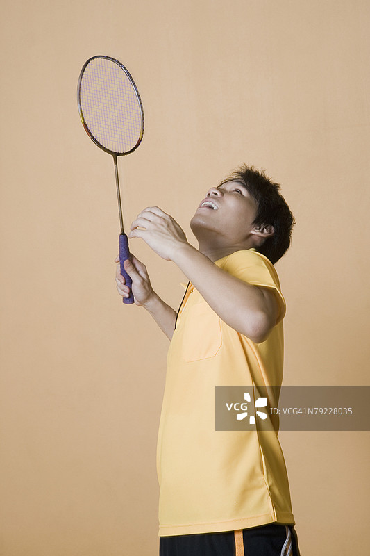 年轻男子打羽毛球的侧面轮廓图片素材