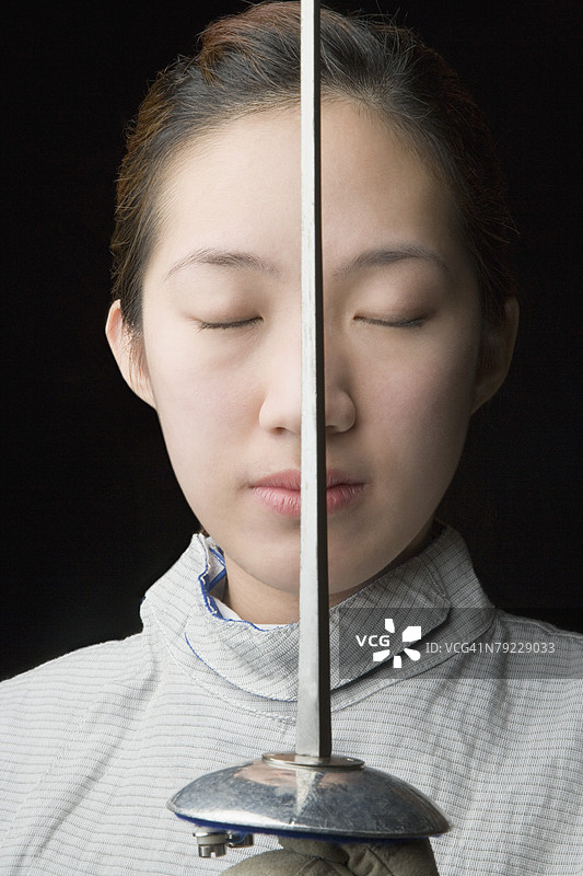 闭上眼睛的女击剑手特写，手持击剑剑。图片素材
