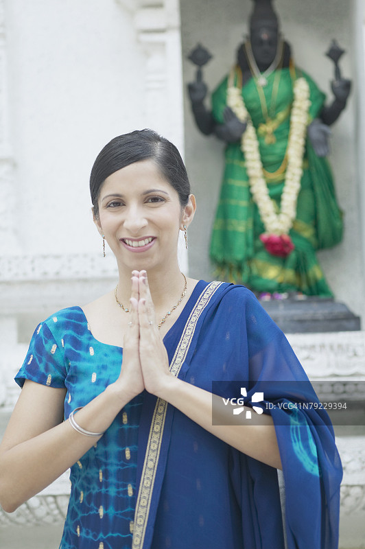 双手合十站在宗教人物面前的中年妇女肖像图片素材