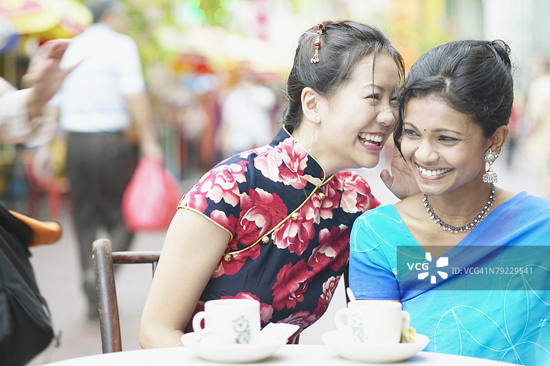年轻女性靠近另一位女性耳边低语的特写镜头图片素材