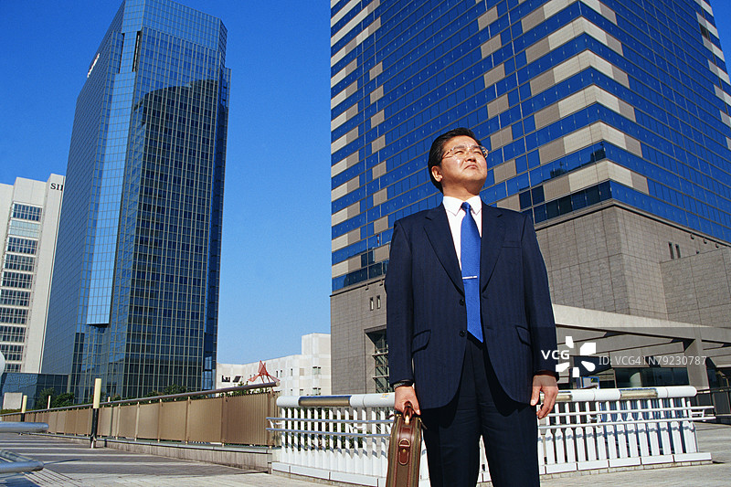 穿着西装的男士站在建筑物前面图片素材