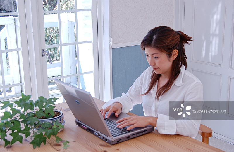 一位年轻女性在家中使用电脑图片素材