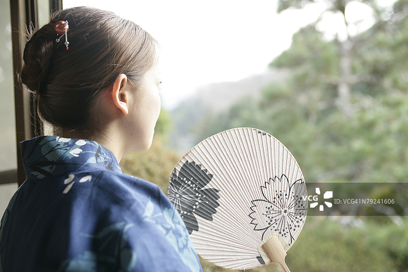 身穿和服、手持扇子的女人，凝视着花园图片素材