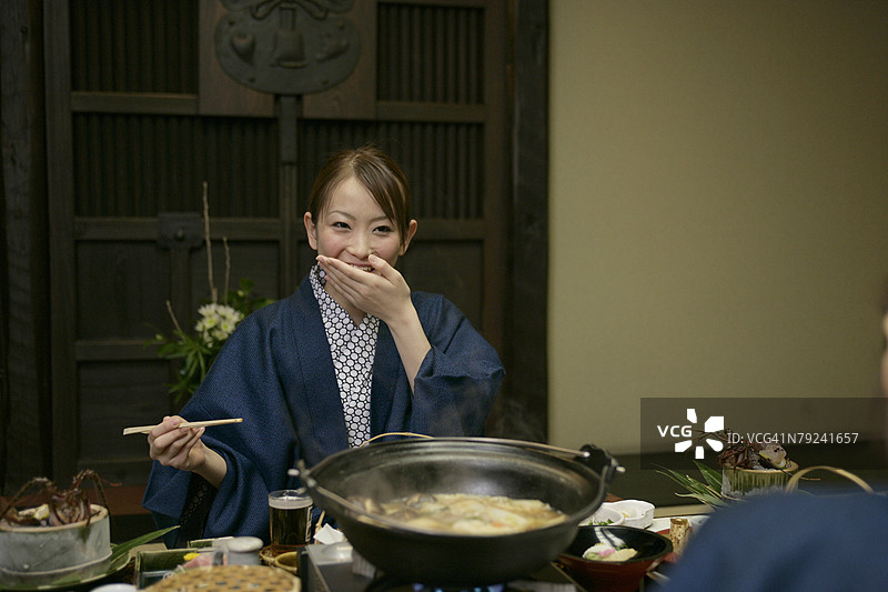 女人一只手拿着筷子，另一只手捂住嘴巴图片素材