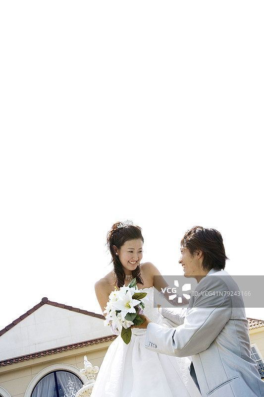 新娘和新郎站在房子前，低角度视图图片素材