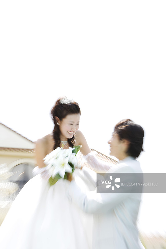 新娘和新郎站在房子前，低角度视图图片素材