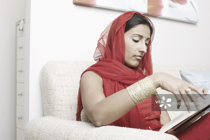 年轻女人坐在沙发上读书图片素材