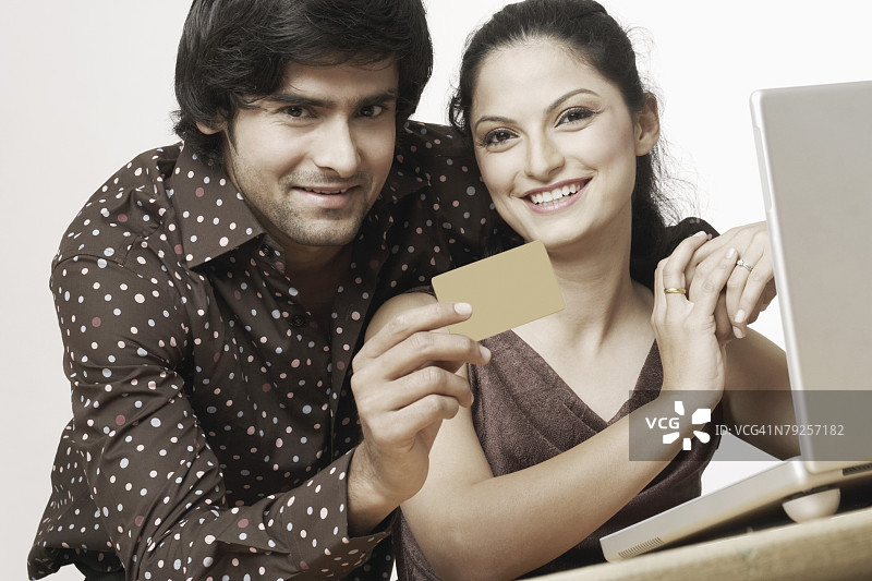 年轻夫妇使用笔记本电脑和信用卡图片素材