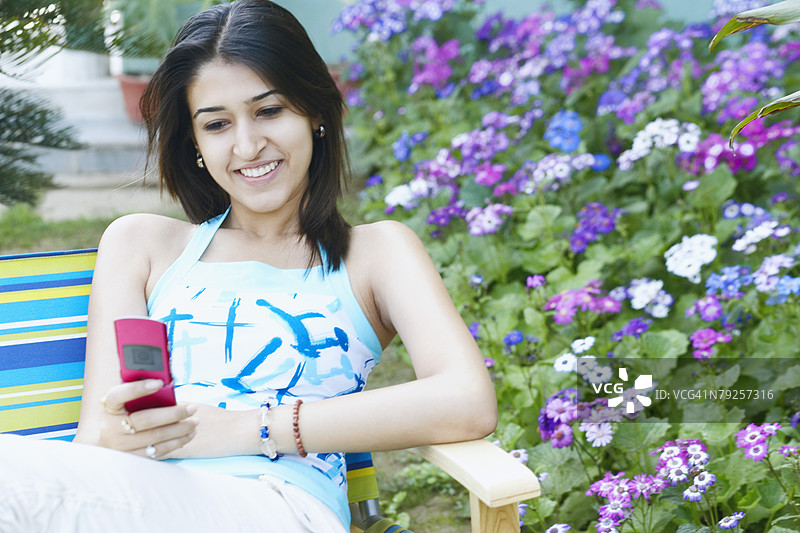 年轻女性手持手机微笑图片素材