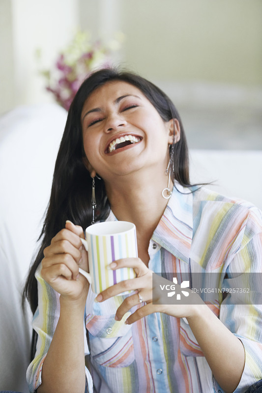 年轻女子手持马克杯欢笑特写图片素材