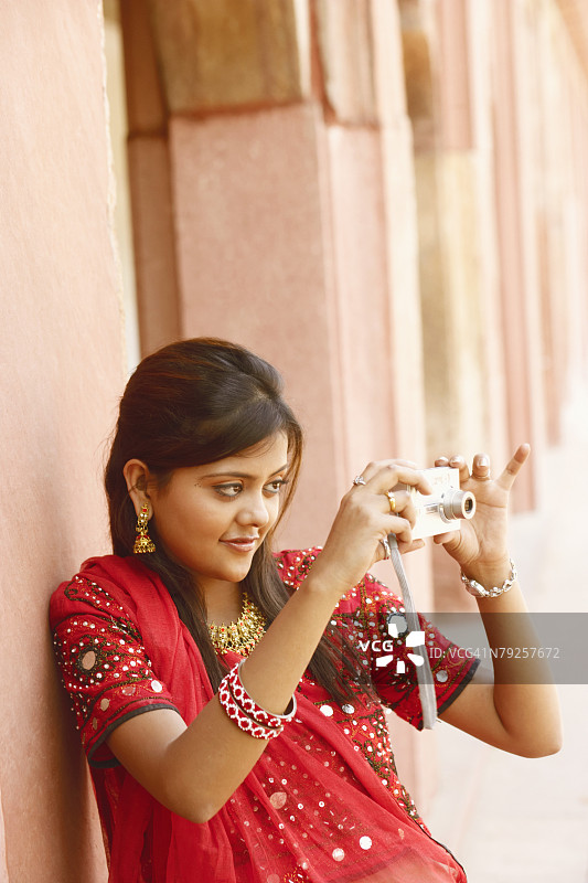 年轻女子在印度北方邦阿格拉堡用数码相机拍照图片素材