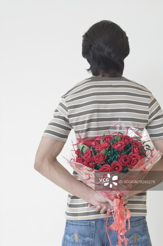 男人背影，手捧鲜花藏在身后图片素材