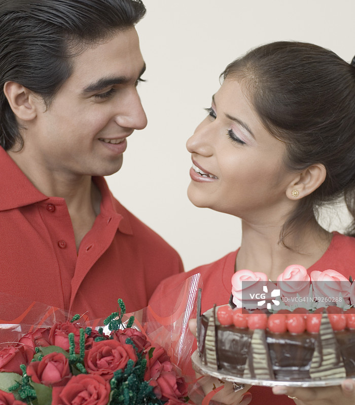 年轻女人拿着巧克力蛋糕看着年轻男人的特写图片素材