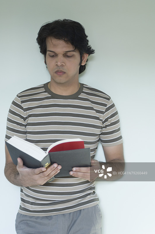 特写：年轻男子站立阅读书籍图片素材