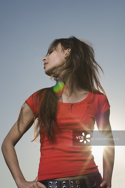 低角度视图的年轻女性双手叉腰站立图片素材