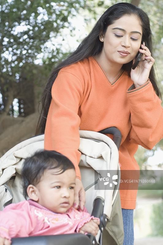 年轻女子和女儿站在一起，正在用手机交谈图片素材