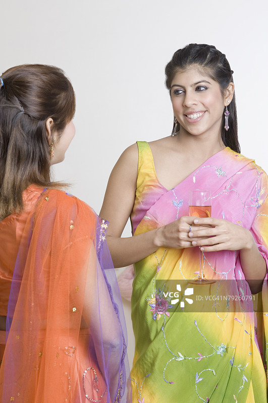 站着手持一杯饮料看着另一位年轻女人的年轻女人图片素材