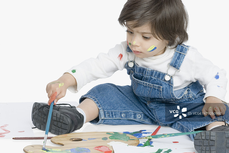 男孩坐着用画笔绘画图片素材