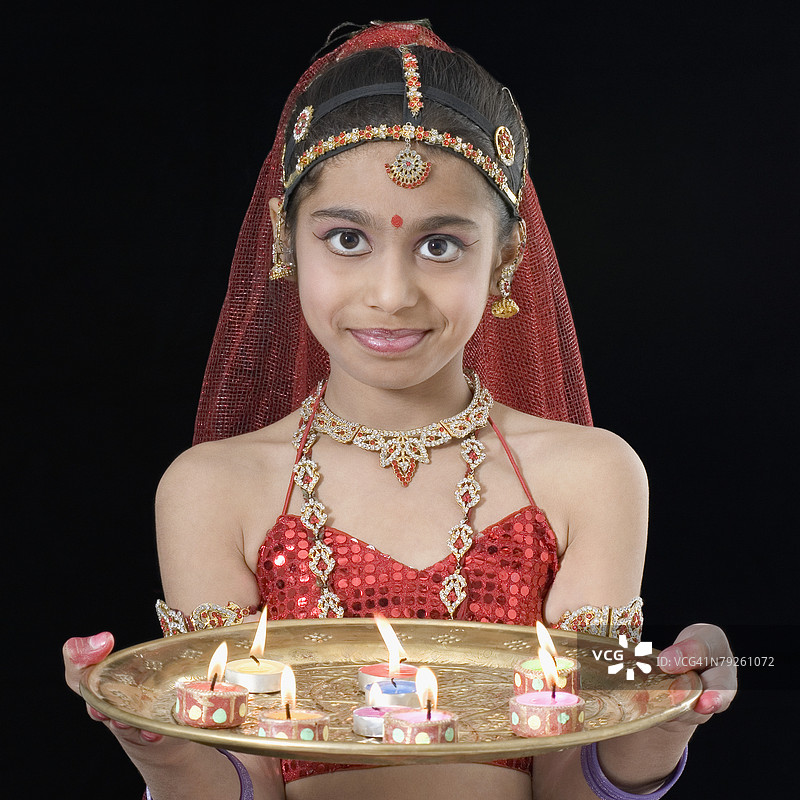女孩手持一盘燃烧的蜡烛的肖像图片素材