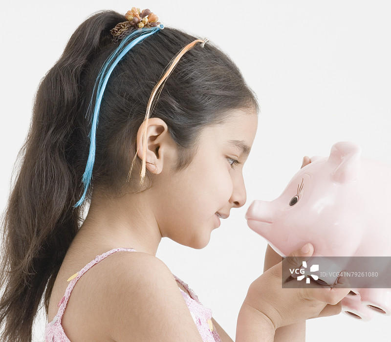 女孩拿着小猪存钱罐的侧面轮廓图片素材