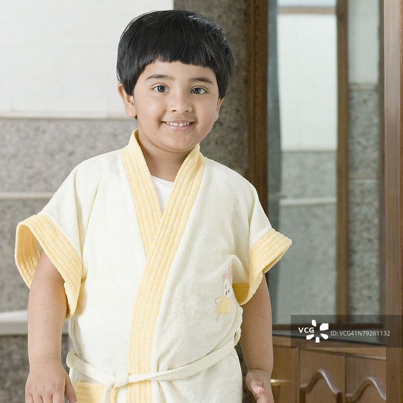 穿着浴袍的女孩在浴室里站着的肖像图片素材