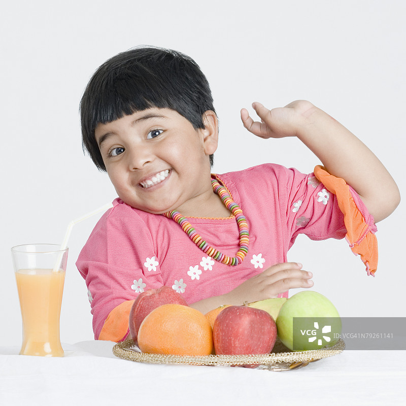 对着面前一盘水果微笑的女孩肖像图片素材