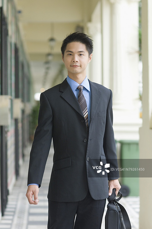 一位手持公文包走路的商人肖像图片素材