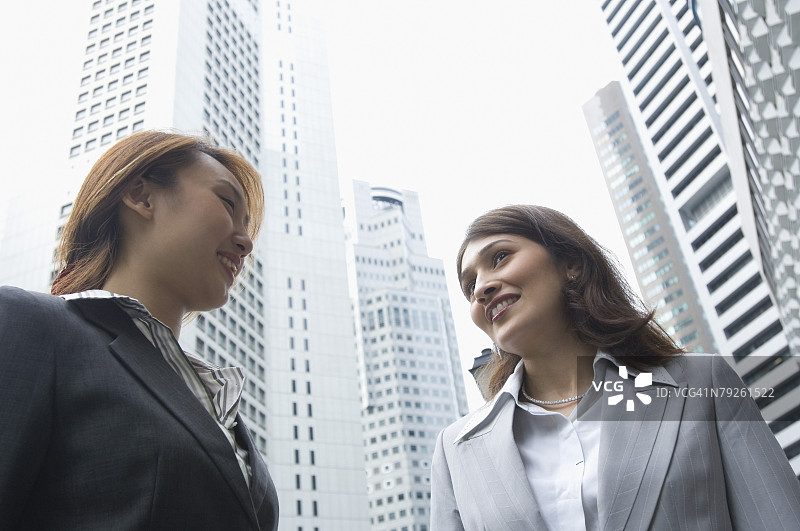 在新加坡，两位女商人站在一起微笑的低角度视图图片素材