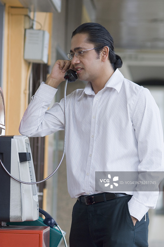 中年男人在公用电话亭打电话图片素材