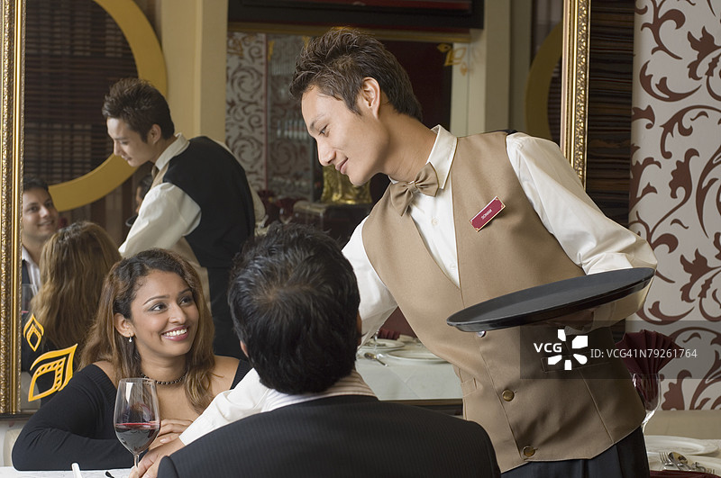 服务员为一对年轻情侣倒酒的特写镜头图片素材