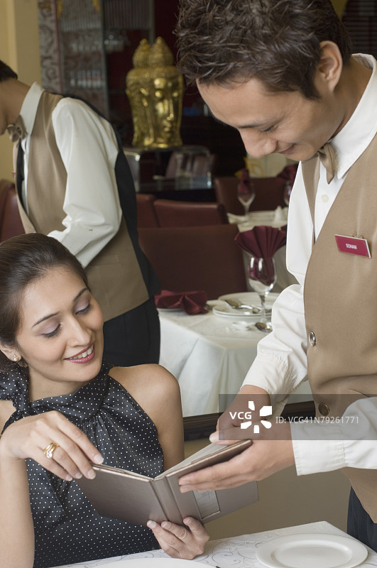 服务员向年轻女子展示菜单的特写图片素材