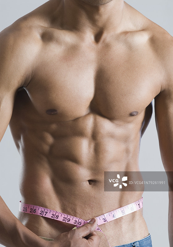 年轻男子用卷尺测量腰围的中段视角图片素材