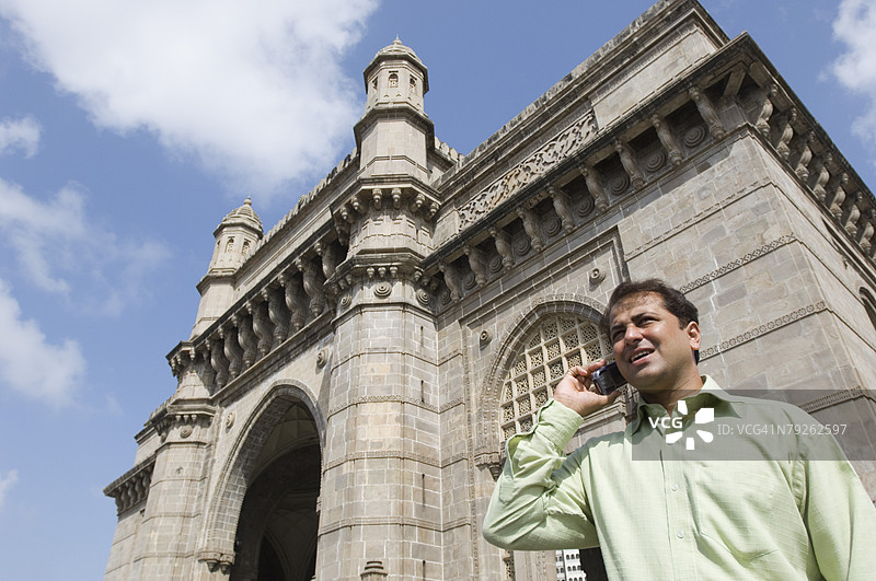 低角度视图的商人在印度孟买的印度门打电话图片素材
