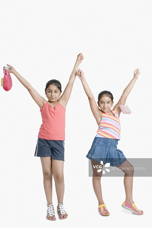两个女孩摆姿势，双臂高举图片素材