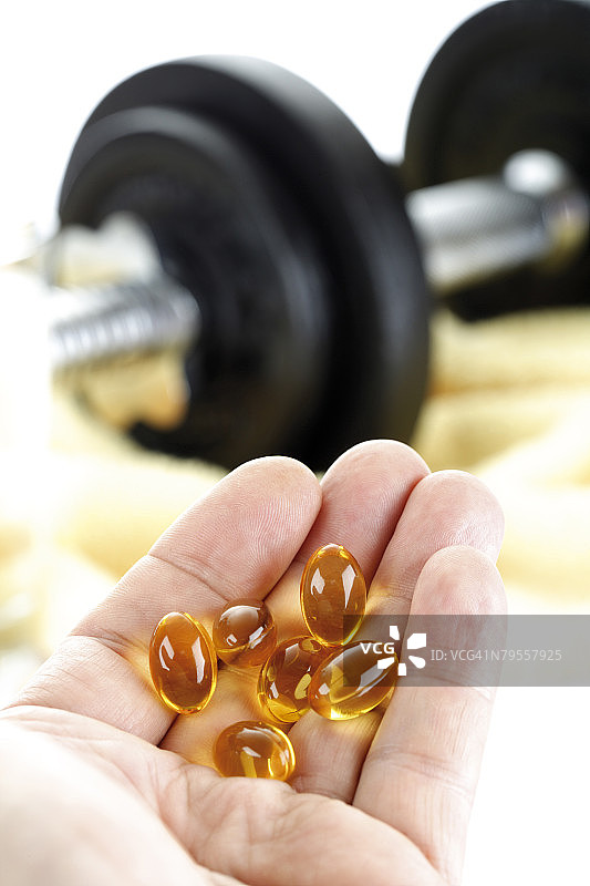 手持药丸，背景为哑铃图片素材