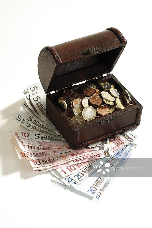 打开的装满硬币的钱箱，立于纸币之上，高角度视图图片素材